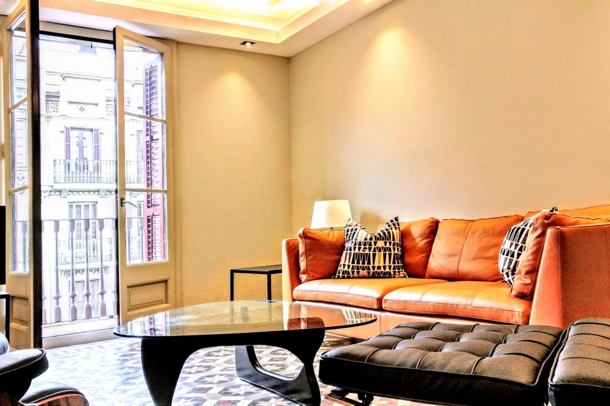 signature leather furniture and sofa at the Dandi luxury apartment for short term rentals in Barcelona. You will relax sitting in the Barcelona chair and ottoman and the Noguchi coffe table that rounds the scene.