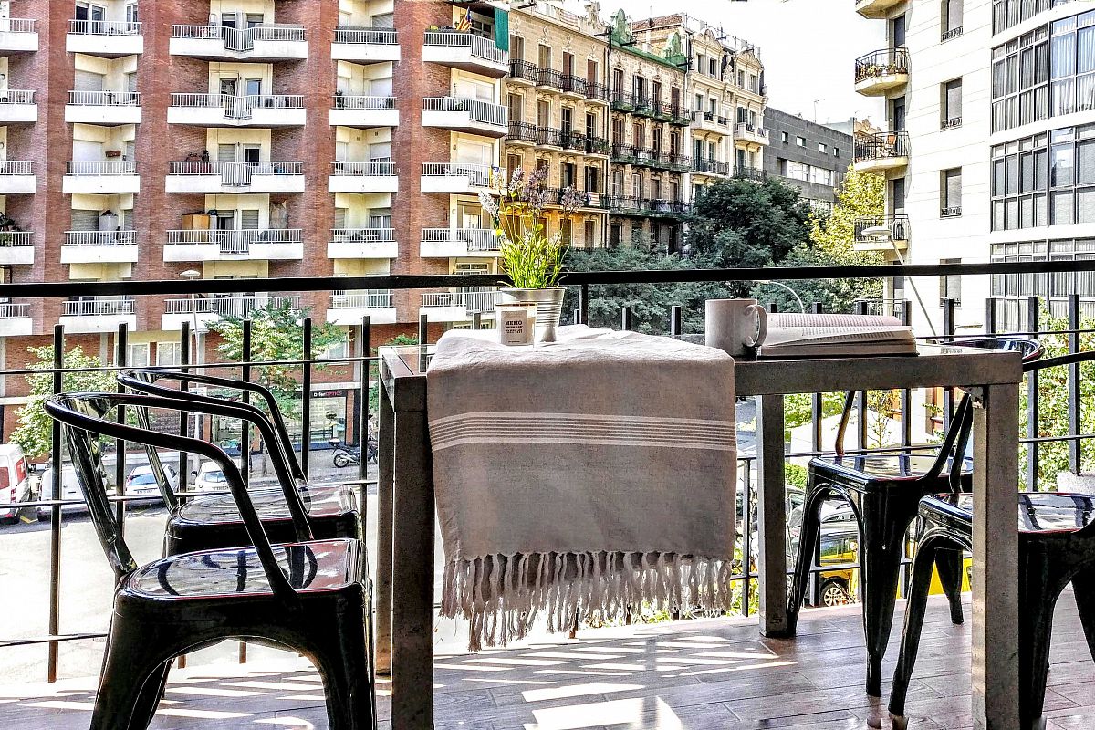 the lovely furnished terrace has a large glass dining table and four metal chairs