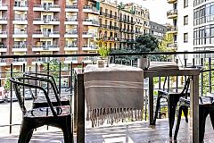 the lovely furnished terrace has a large glass dining table and four metal chairs