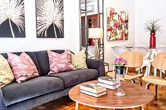 the Noname apartment living area with palm tree leaves paintings and fluffy cushions in the sofa is perfect for vacation getaways in Barcelona Eixample left