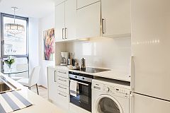 fully equipped pristine white kitchen with washer and dryer