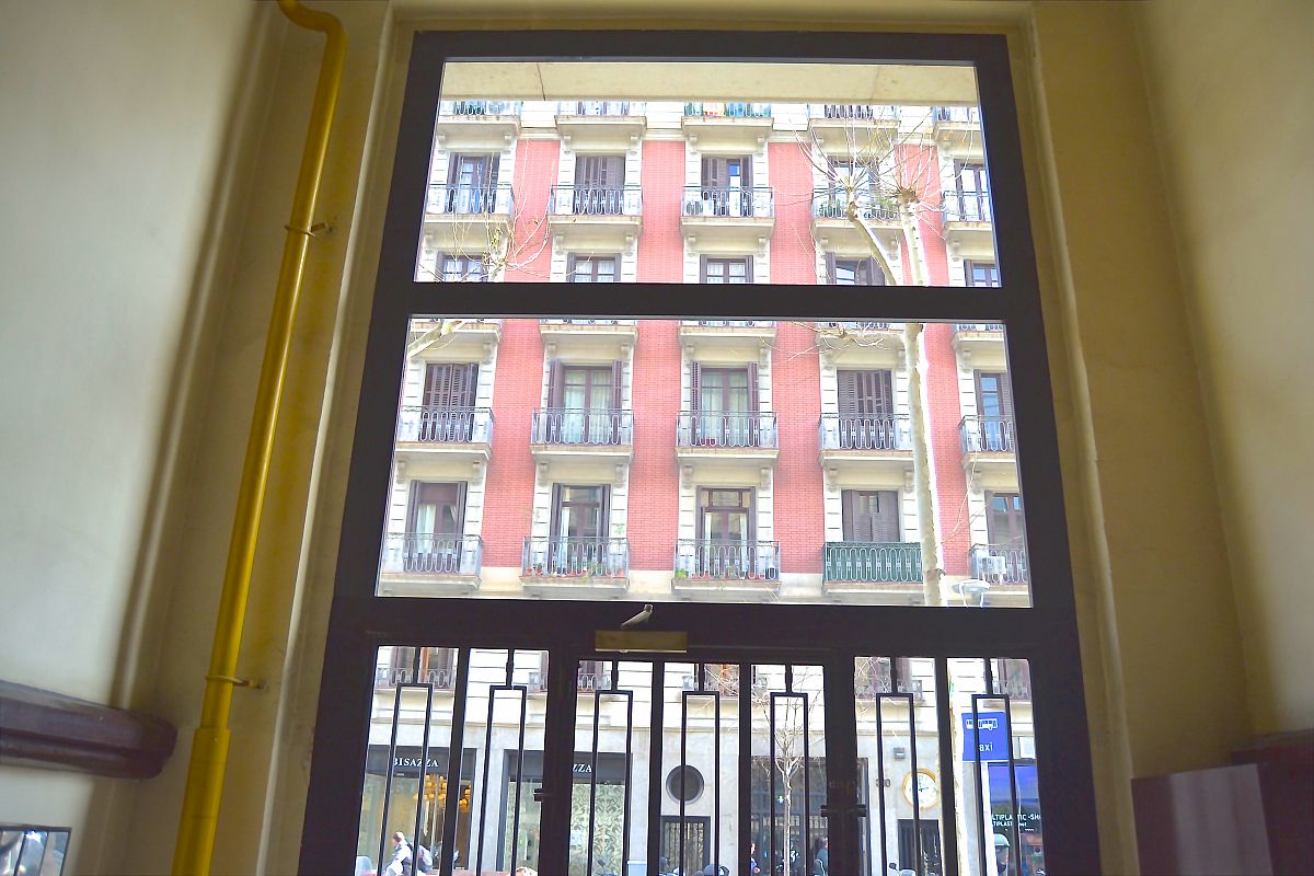 dramatic entrance glass and iron door to the building that houses this LaMimosa luxury apartment for rent in Barcelona Eixample 