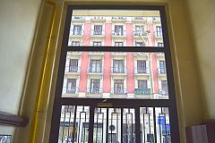 dramatic entrance glass and iron door to the building that houses this LaMimosa luxury apartment for rent in Barcelona Eixample 
