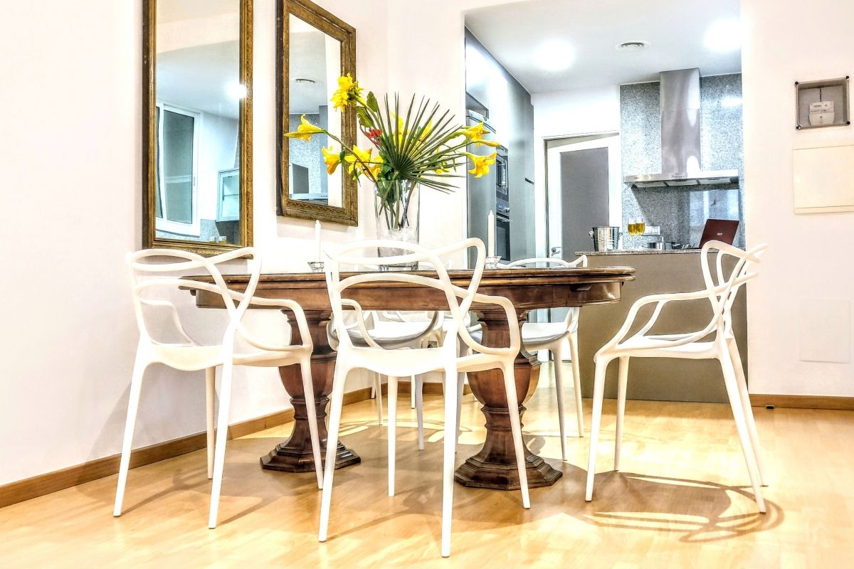 A vintage mahogany table is a luxury for six people, who may gracefully sit on six Curve dining chairs by Kartell at the Parsifal with balcony luxury apartment for short term rentals in Barcelona