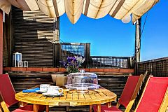 Jollie penthouse with Terrace in Les Corts Barcelona boasts a terrific terrace under a wooden canopy dressed with a white sunshade, and flowing curtains